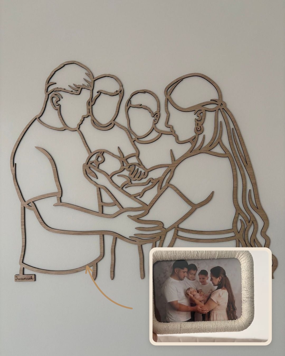 Linienporträt aus Holz einer Familie mit zwei Söhnen und ihrem Neugeborenen, neben dem gerahmten Foto