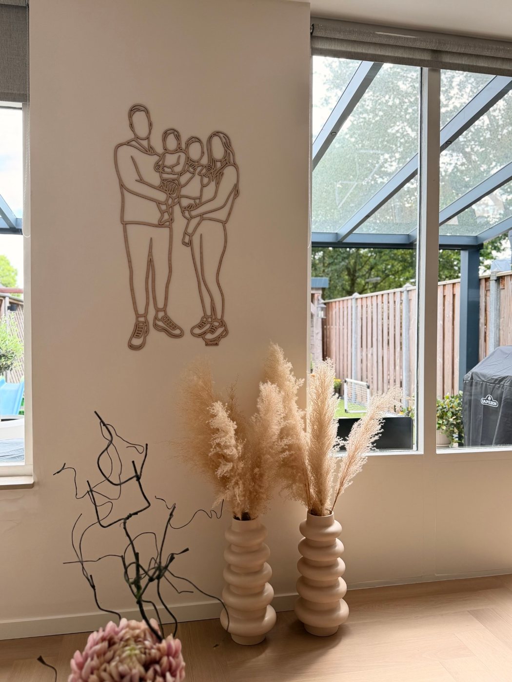 Linienporträt aus Holz einer Familie zwischen Fenster und Wintergarten