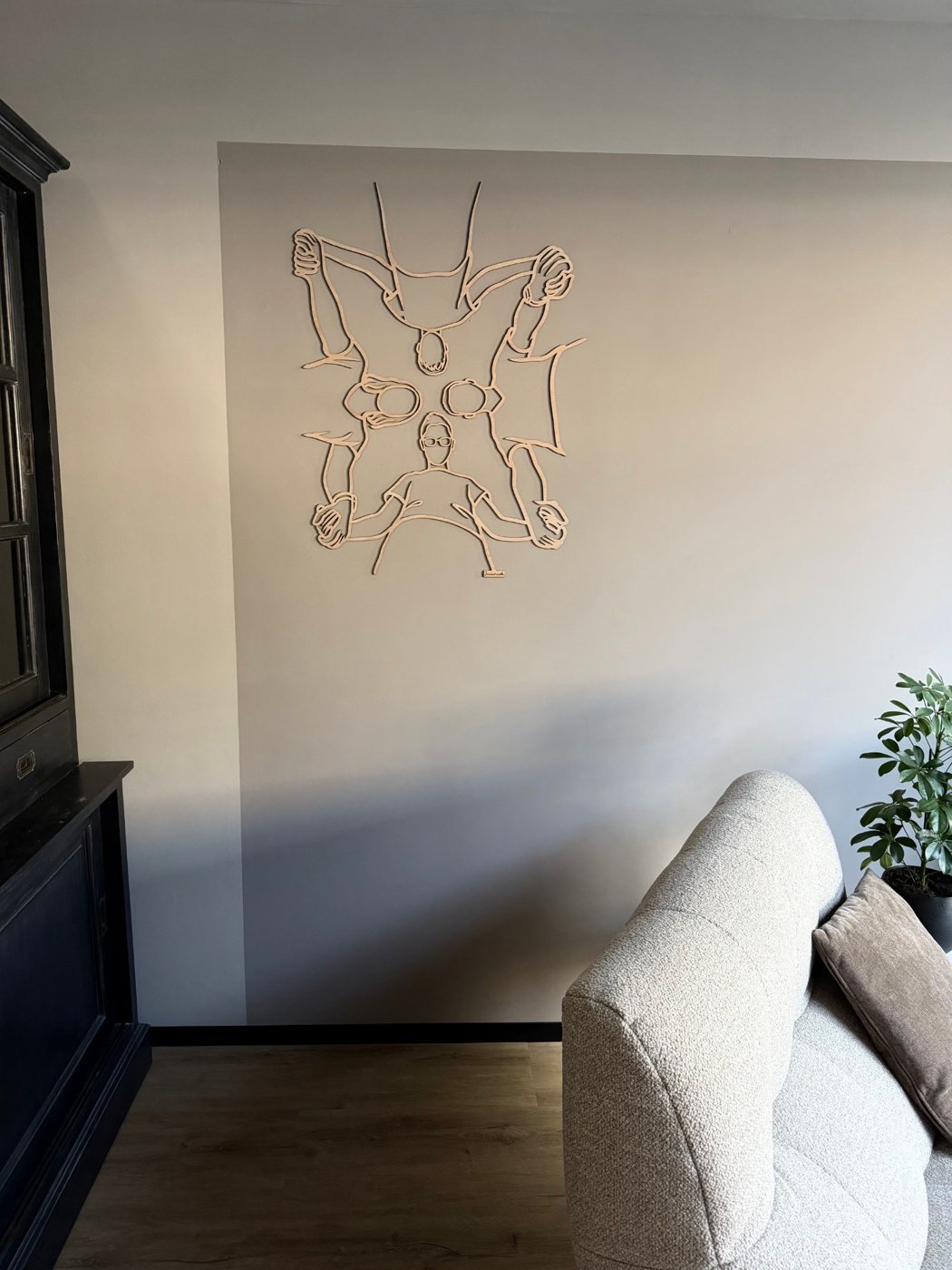 Linienporträt aus Holz von vier Personen von oben gesehen, über dem Sofa