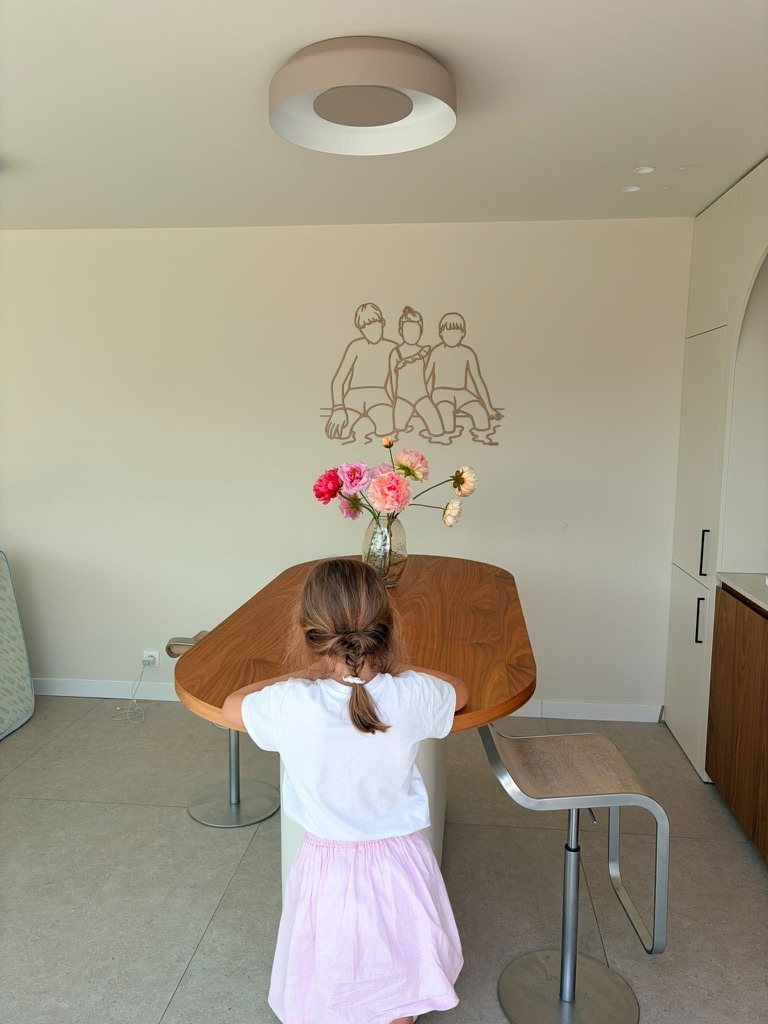 Linienporträt aus Holz von drei Kindern über dem Esstisch