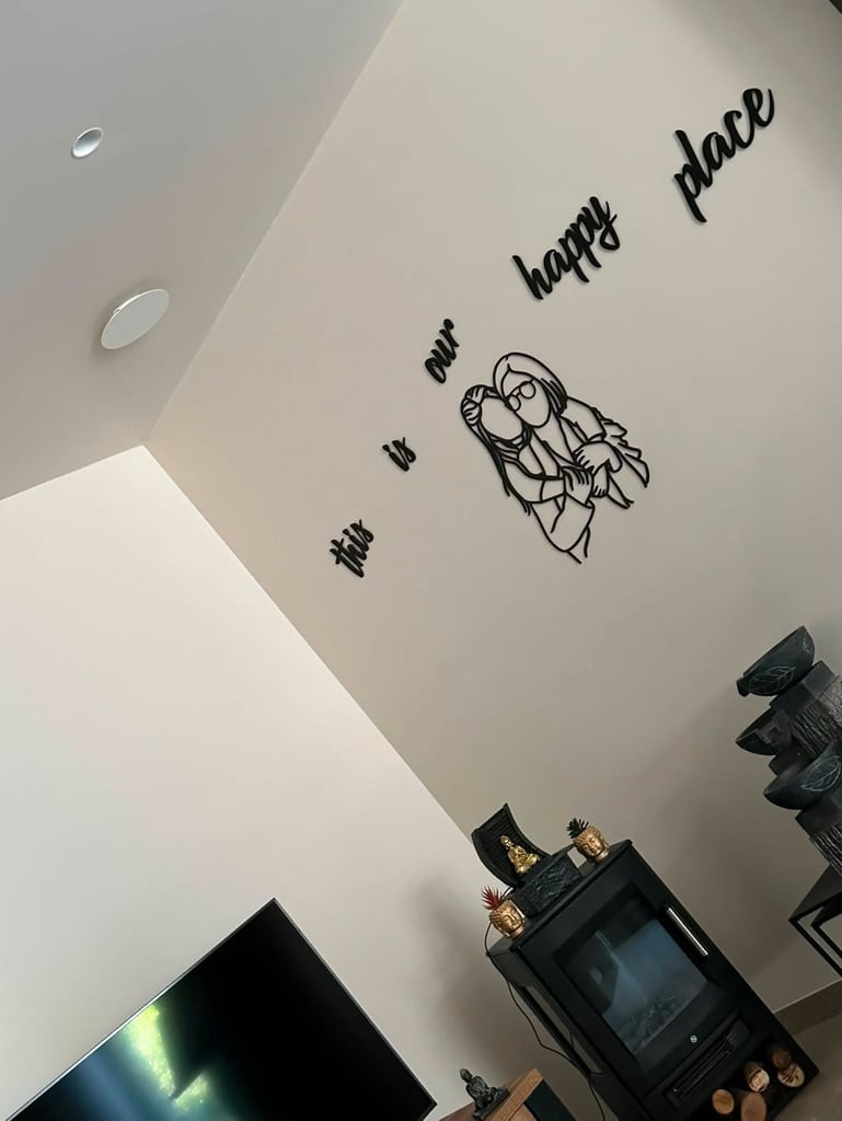 Schwarzes Linienporträt aus Holz mit dem Text „this is our happy place“ über einem Holzofen