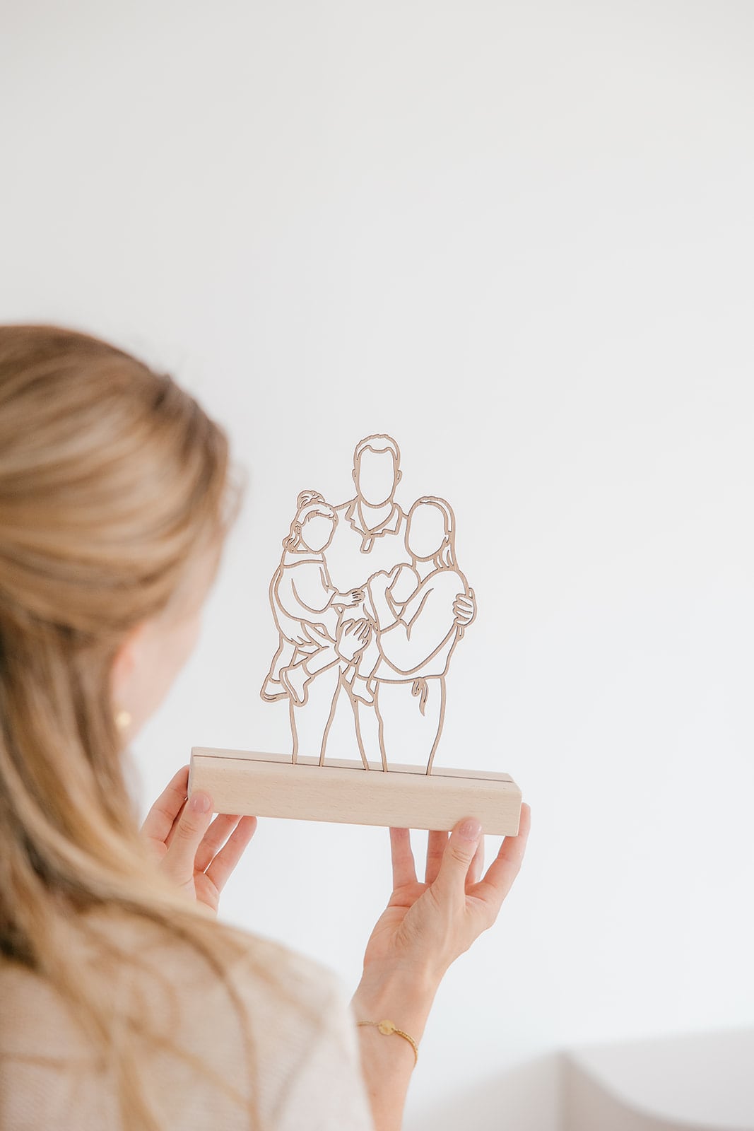 Standmodell aus Holz einer Familie mit ihrem Neugeborenen, in den Händen gehalten