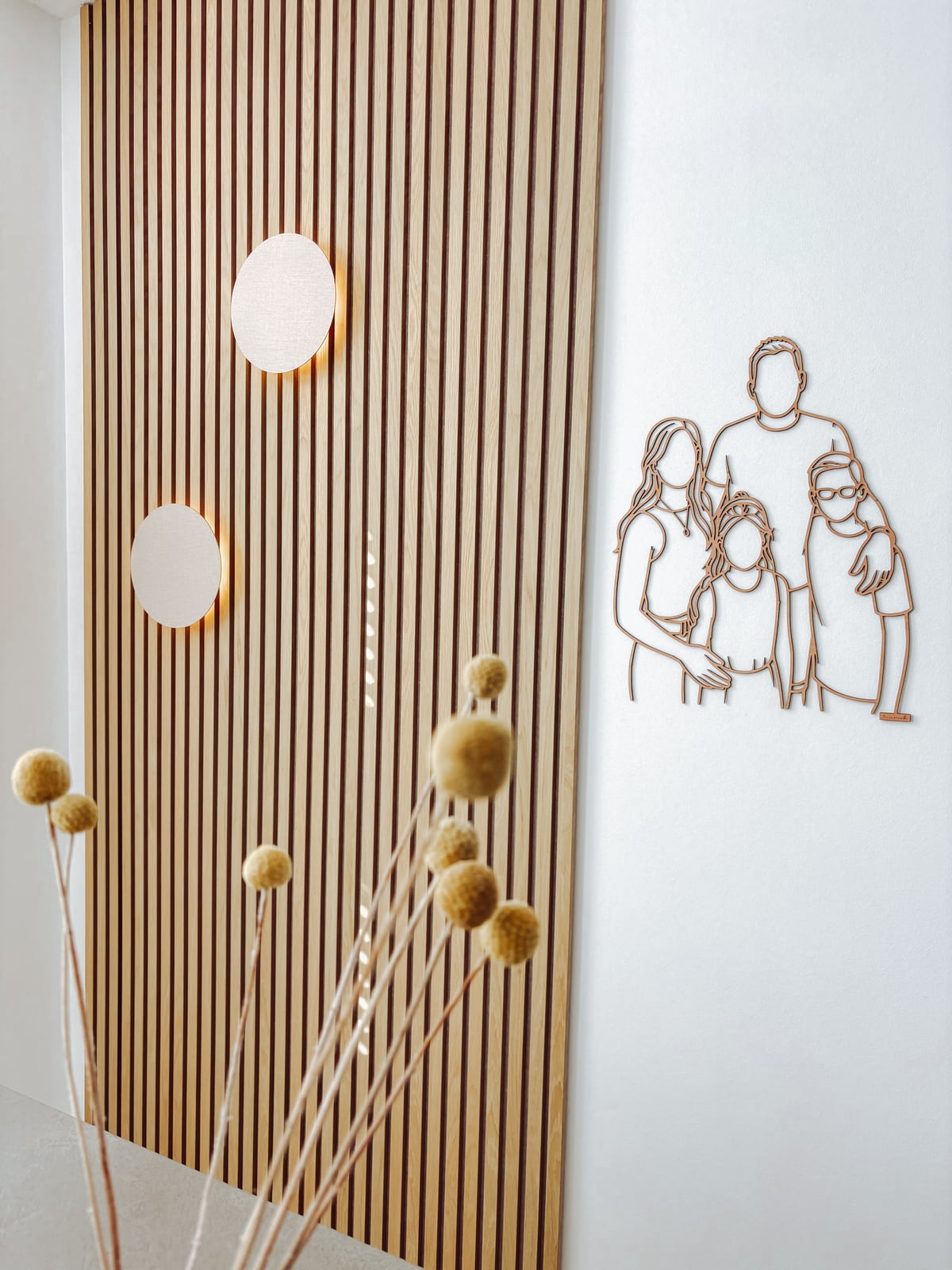 Linienporträt aus Holz von einer Familie neben einer Holzlattenwand