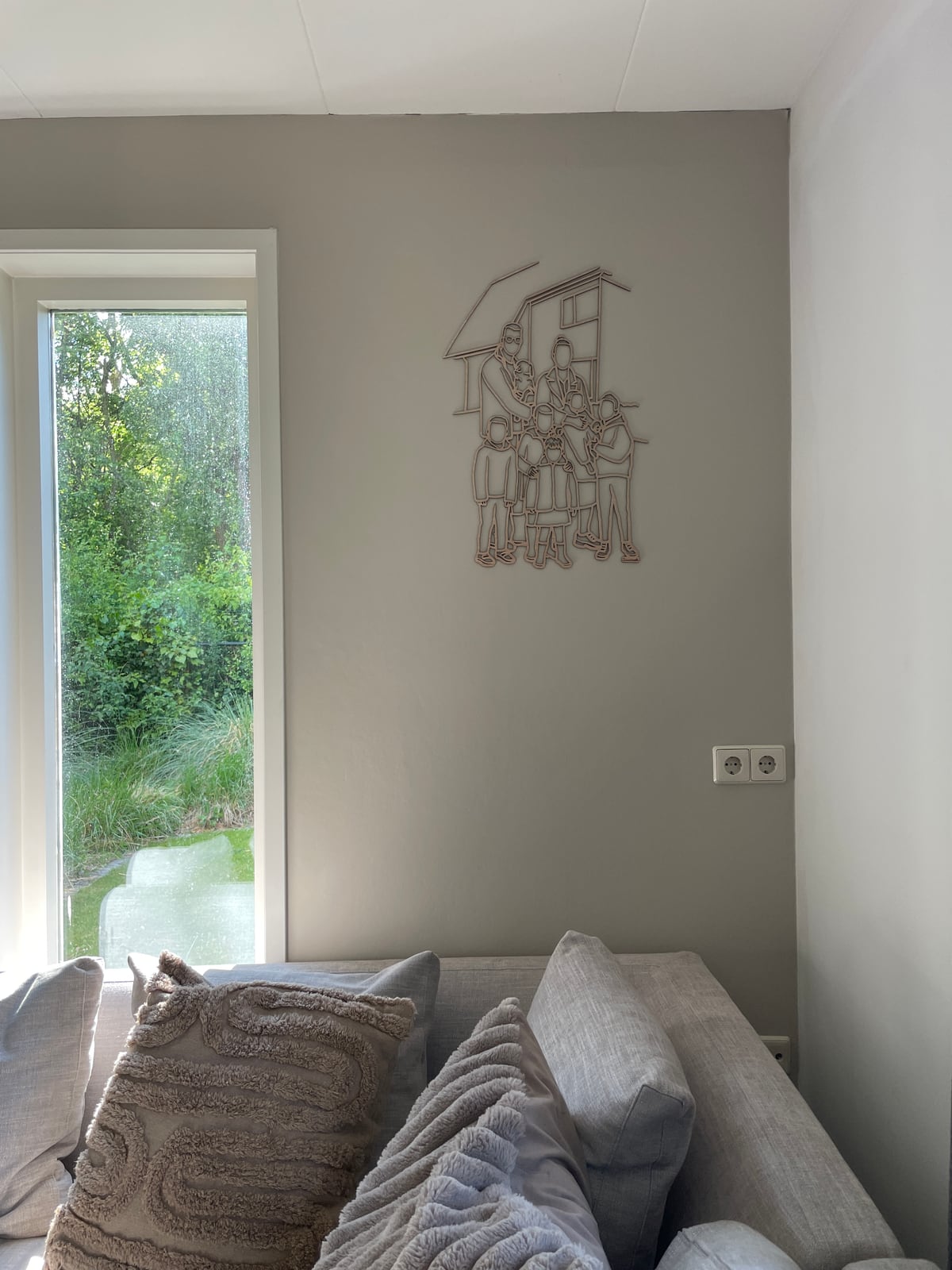 Linienporträt aus Holz einer großen Familie vor ihrem Haus, über dem Sofa