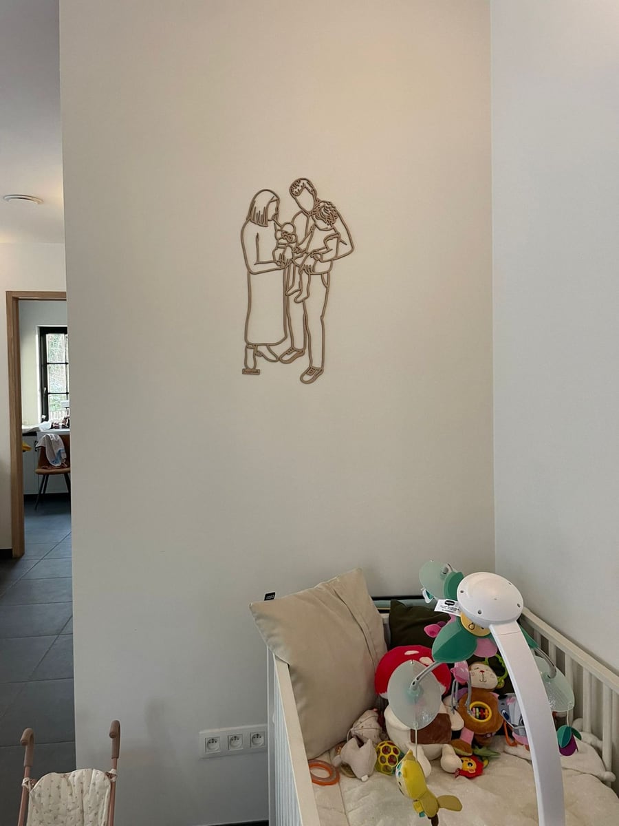 Linienporträt aus Holz einer jungen Familie mit Baby und Kleinkind, über dem Bettchen