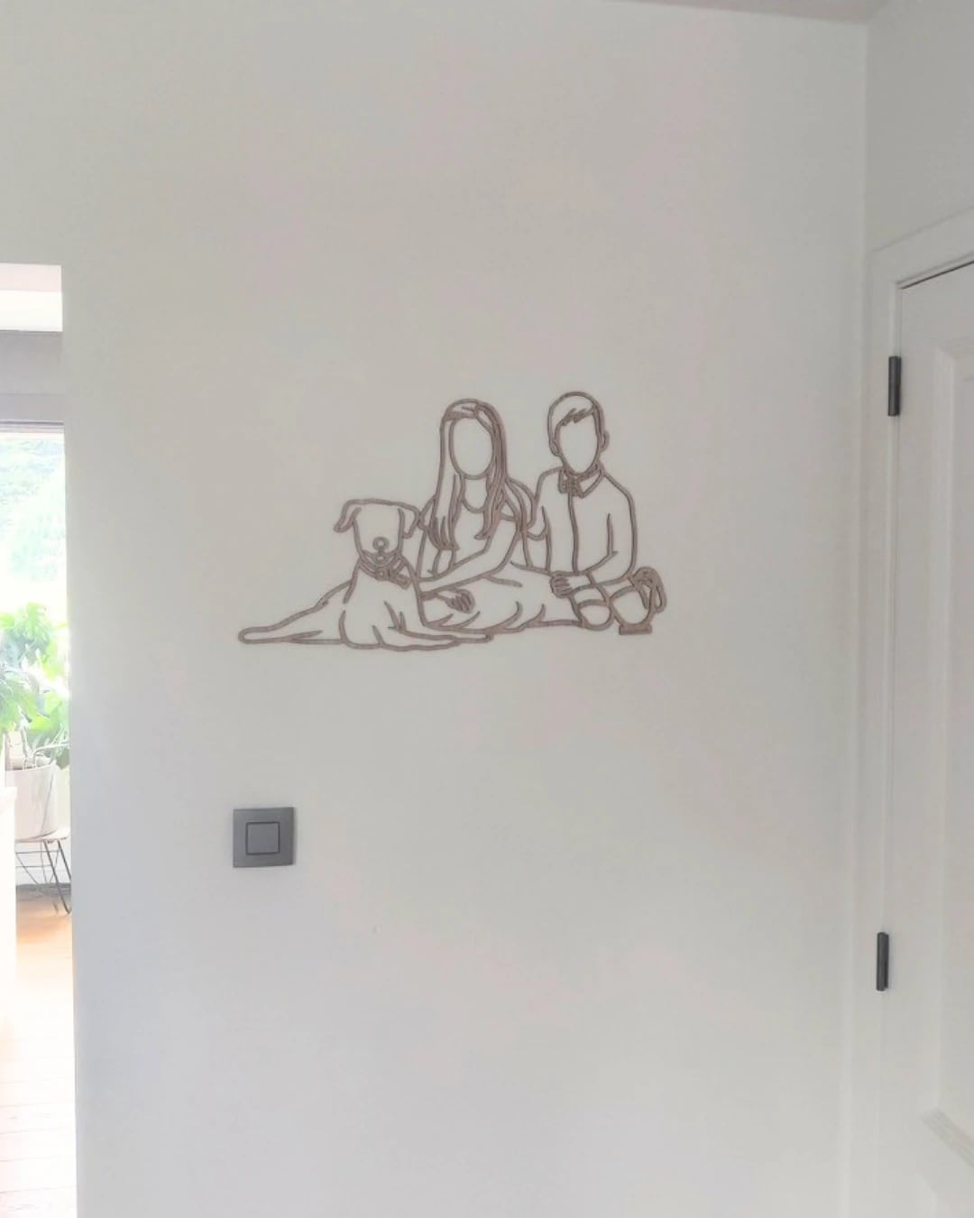 Linienporträt aus Holz von einem Paar mit ihrem Hund an der Wand