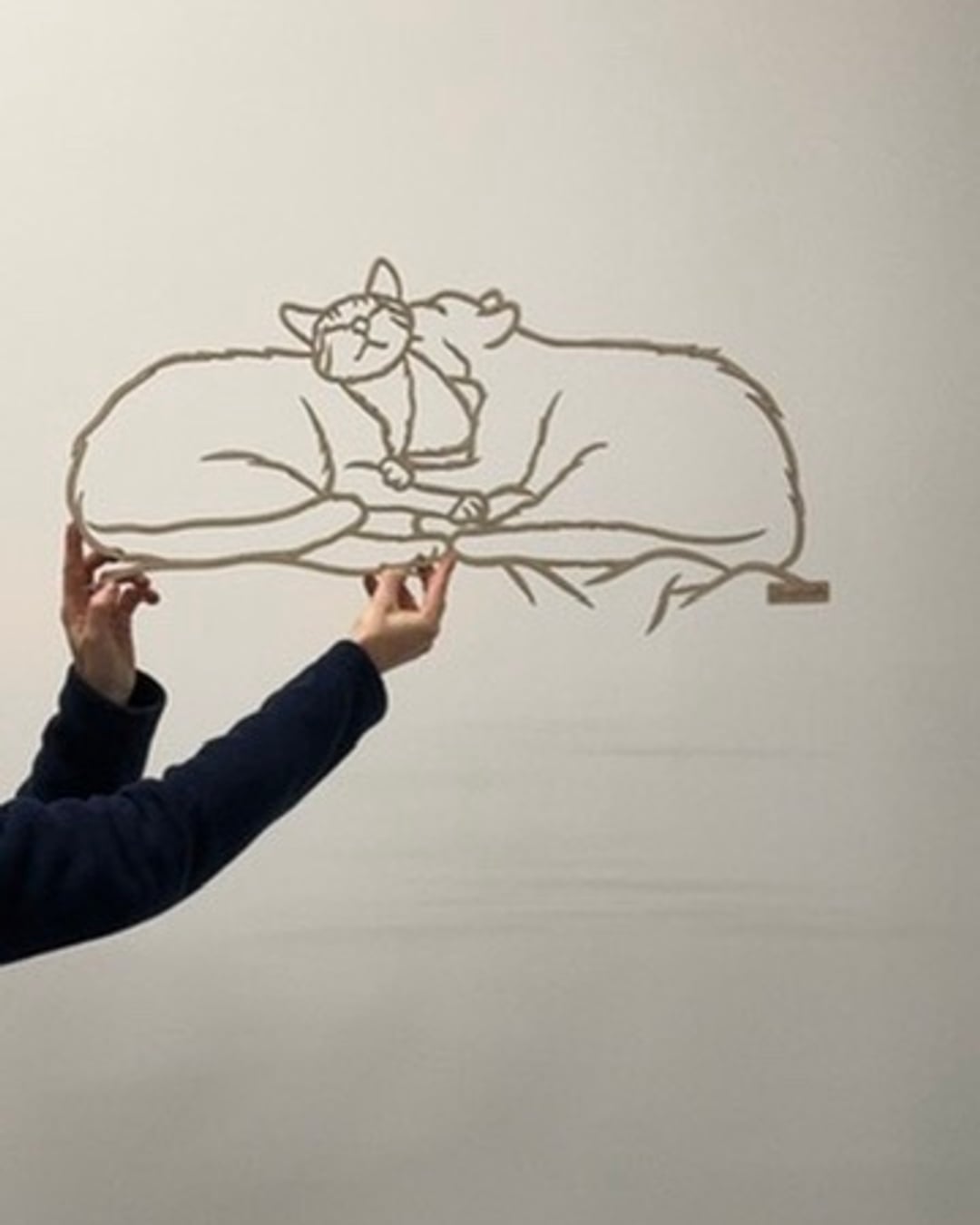 Linienporträt aus Holz von zwei Katzen, die aneinandergekuschelt liegen