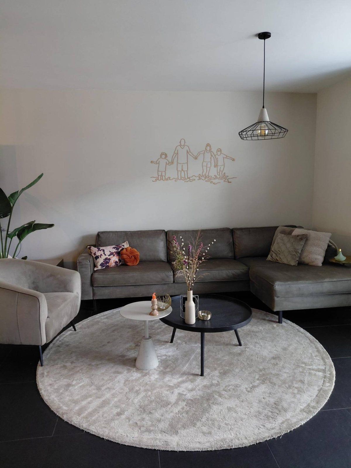 Linienporträt aus Holz einer Familie über dem Sofa im Wohnzimmer